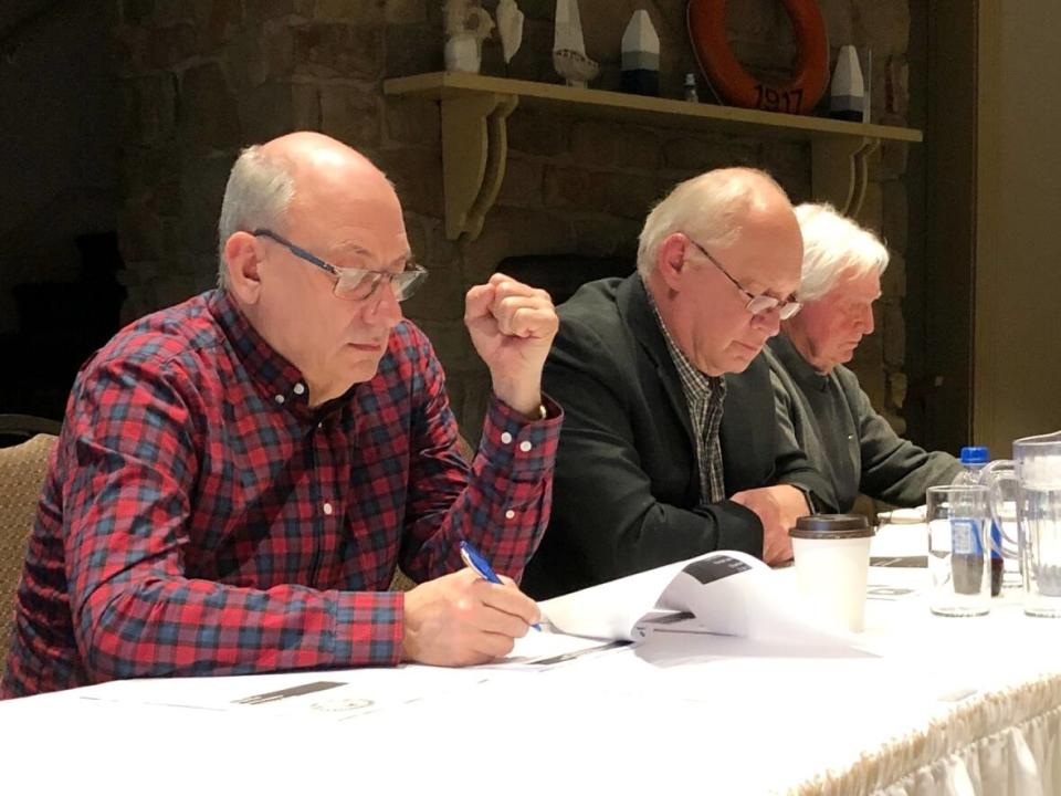 Village of Baddeck commissioner Ian Nicholson, interim CAO Maris Freimanis and former commission chair Bill Marchant review the finances during a public meeting in April. (Tom Ayers/CBC - image credit)