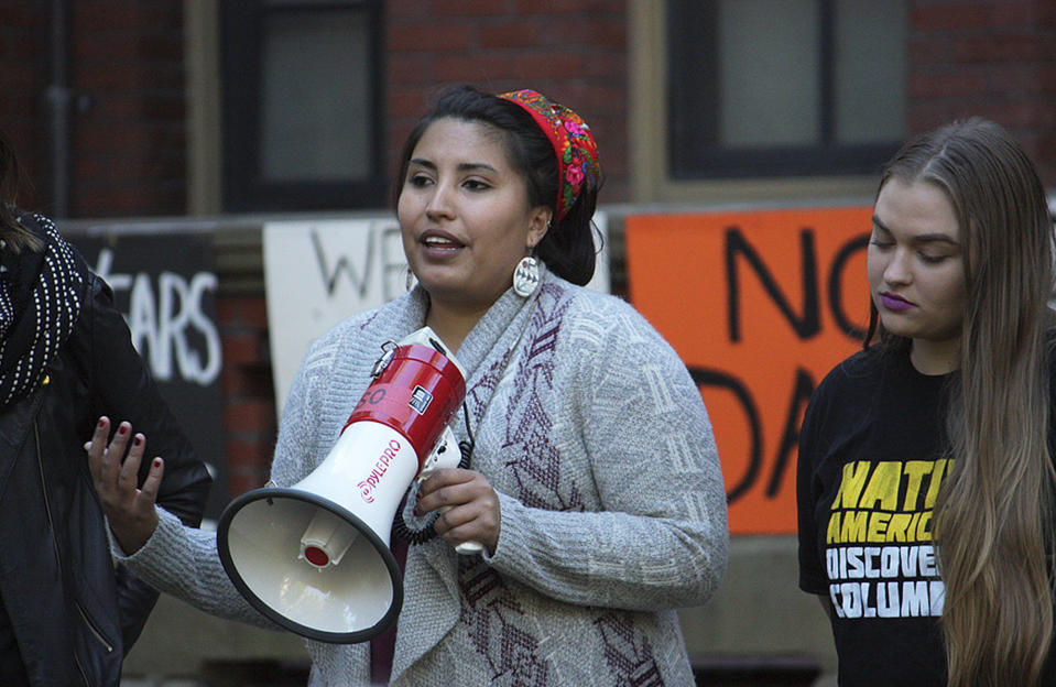 In this 2016 photo provided by Jason Packineau, Danielle Lucero, center, of Isleta Pueblo, New Mexico, speaks during Indigenous Peoples' Day at Harvard University in Cambridge, Mass. The clash between Massachusetts Sen. Elizabeth Warren and President Donald Trump over her Native American heritage highlights the varying methods tribes use to decide who belongs. The decision has wide-ranging consequences for Native American communities and their relationship with the federal government. (Jason Packineau/via AP)