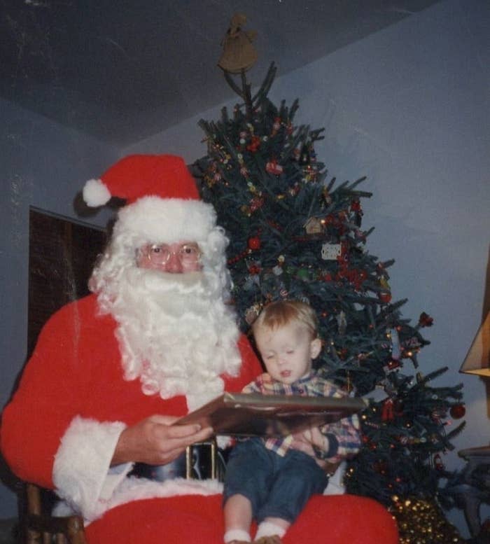 A little boy sitting on Santa's lap in front of a Christmas tree