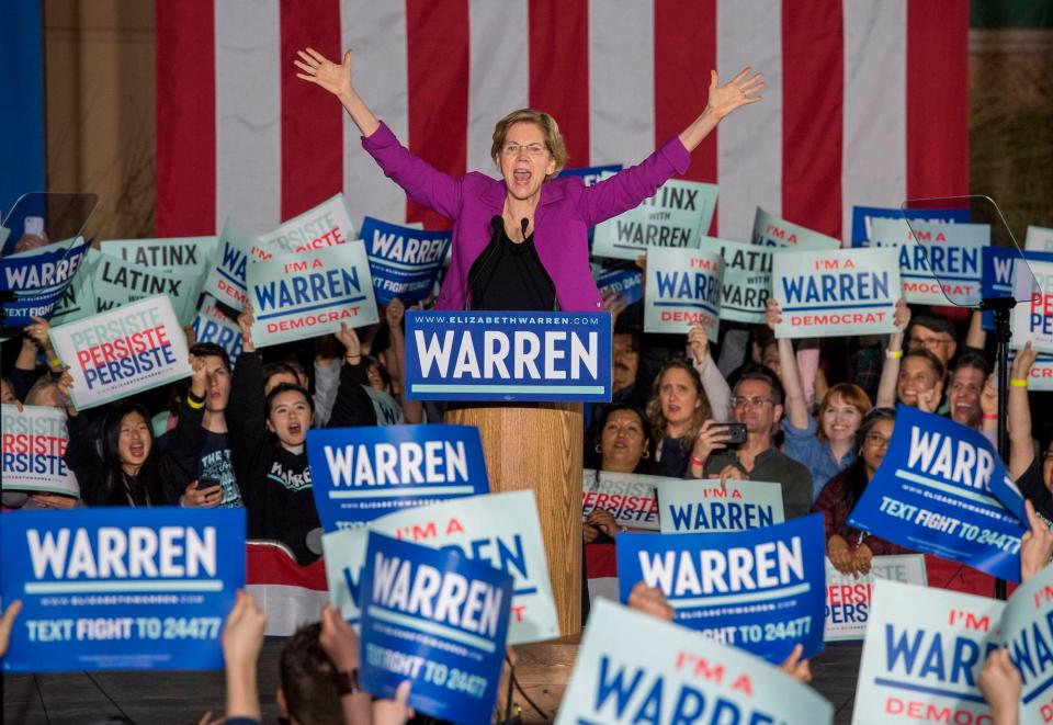 Democratic Sen. Elizabeth Warren of Massachusetts, her arms outstretched overhead in a V-shape, addresses a sea of supporters holding up "I'm a Warren Democrat" signs during a presidential campaign event in Lops Angeles, California.