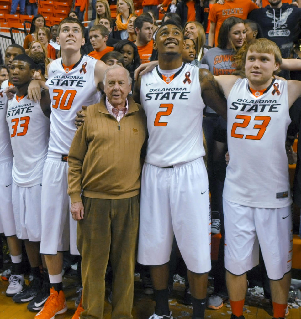 FILE - In this March 2, 2013, file photo, oil tycoon and Oklahoma State supporter T. Boone Pickens, center, celebrates with Oklahoma State's basketball team members Marcus Smart (33), Mason Cox (30), Le'Bryan Nash (2) and Alex Budke, right, following the team's win over Texas in an NCAA college basketball game in Stillwater, Okla. Pickens, a brash and quotable oil tycoon who grew even wealthier through corporate takeover attempts, died Wednesday, Sept. 11, 2019. He was 91. (AP Photo/Brody Schmidt, File)