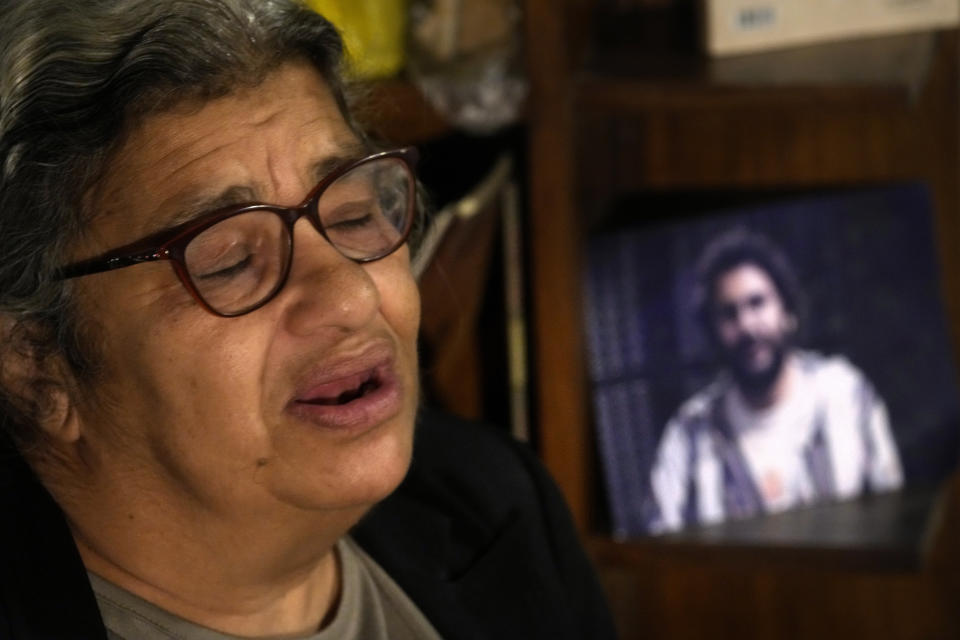 Laila Soueif, mother of jailed pro-democracy activist Alaa Abdel-Fattah, who this week escalated a food and water strike demanding his release, speaks during an interview with the Associated Press in front of his picture at her home in Cairo, Egypt, Thursday, Nov. 10, 2022. Abdel-Fattah, who has been in prison for most of the past decade, is serving a five-year sentence on charges of disseminating false news for retweeting a report in 2019 that another prisoner died in custody. (AP Photo/Amr Nabil)