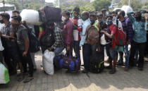 People wearing masks stand in a queue for a train at Lokmanya Tilak Terminus in Mumbai, India, Sunday, April 11, 2021. India is reporting a surge in infections, which according to experts is due in part to growing disregard for social distancing and mask-wearing in public spaces. (AP Photo/Rafiq Maqbool)