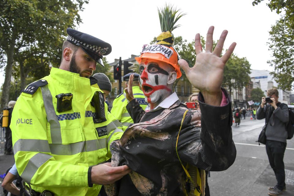 A climate activist is detained by police as others gather at Parliament Street in London, Monday, Oct. 7, 2019. London Police say they've arrested 21 climate change activists over the past few days as the Extinction Rebellion group attempts to draw attention to global warming. (AP Photo/Alberto Pezzali)