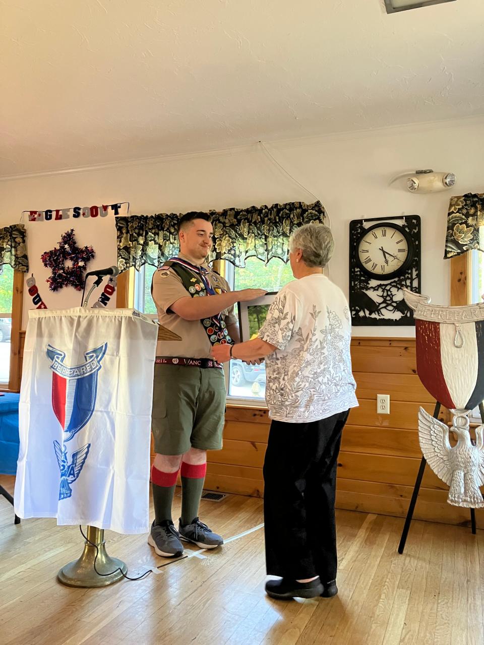 Michael Newton presents Donna Bresnahan with a photograph of a trail sign at the Cummings Conservation Area. Newton designed the sign in honor of her late husband, John Bresnahan, a longtime Troop 9 scoutmaster.