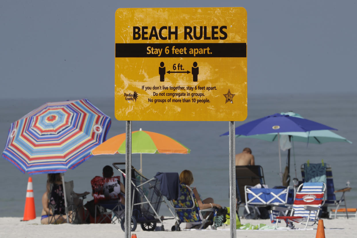 Beachgoers sunbathe near a beach rules sign after Clearwater Beach officially reopened to the public on May 4, 2020, in Clearwater Beach, Fla. (Chris O'Meara/AP)