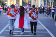 Protesters wear old Belarusian national flags walk during an opposition rally to protest the official presidential election results in Minsk, Belarus, Sunday, Sept. 20, 2020. Tens of thousands of Belarusians calling for the authoritarian president to resign marched through the capital on Sunday as the country's wave of protests entered its seventh week. Hundreds of soldiers blocked off the center of Minsk, deploying water cannon and armored personnel carriers and erecting barbed wire barriers. (AP Photo/TUT.by)