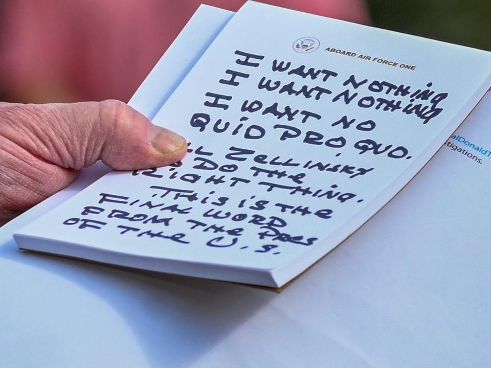 Donald Trump holds what appears to be a prepared statement and handwritten notes reading "no quid pro quo"