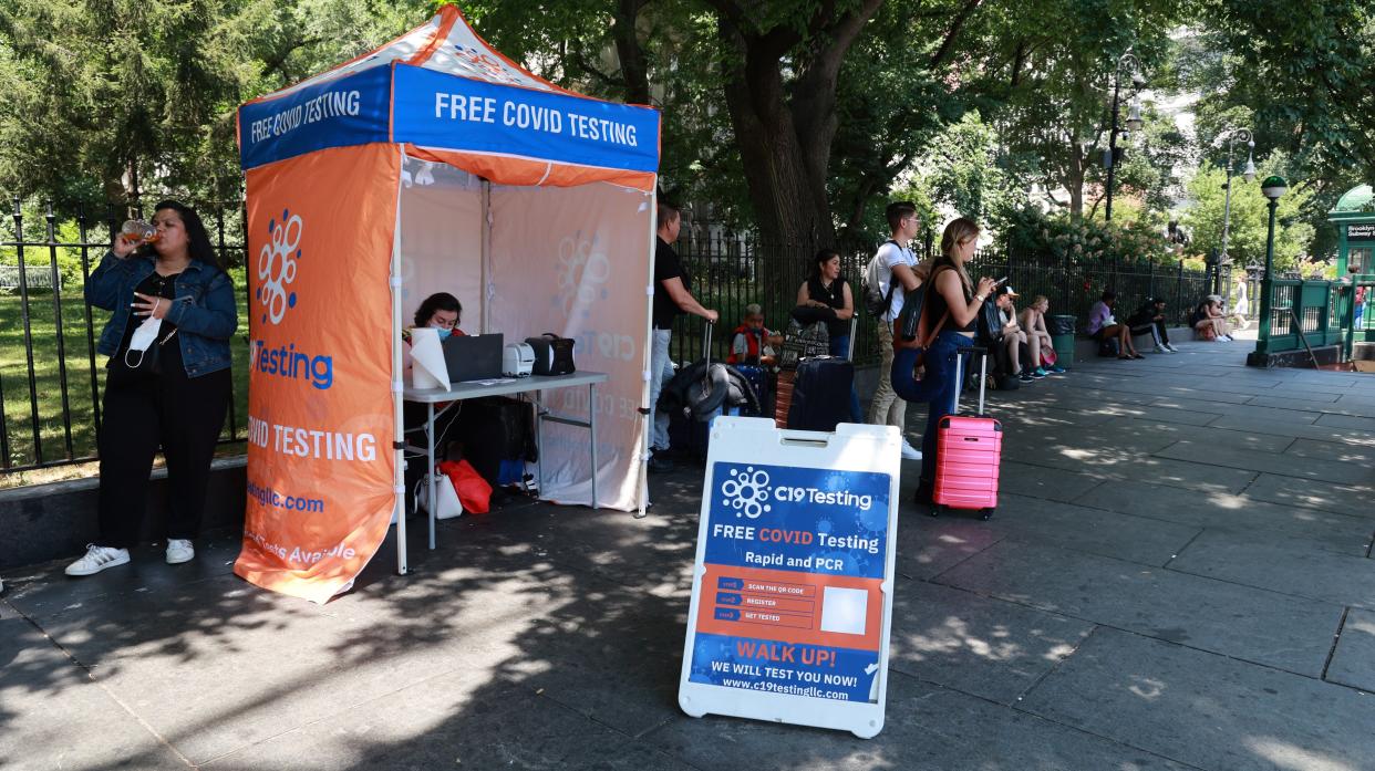 People walk past a COVID-19 test site in City Hall Park near the Brooklyn Bridge in lower Manhattan, New York.