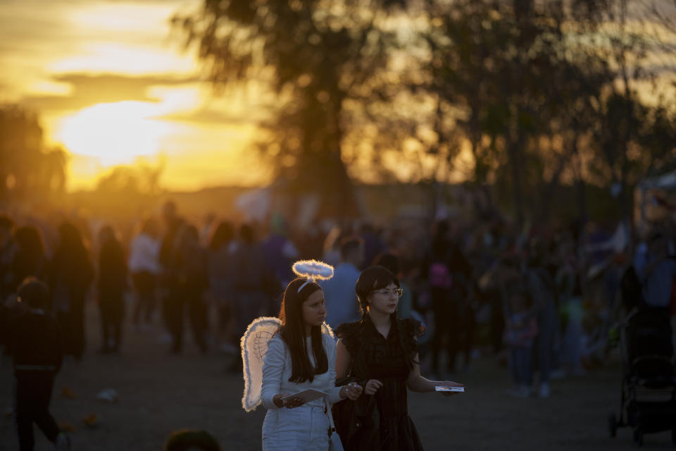 The setting sun illuminates participants at the West Side Hallo Fest, a Halloween festival in Bucharest, Romania, Saturday, Oct. 28, 2023. Tens of thousands streamed last weekend to Bucharest's Angels' Island peninsula for what was the biggest Halloween festival in the Eastern European nation since the fall of Communism. (AP Photo/Andreea Alexandru)