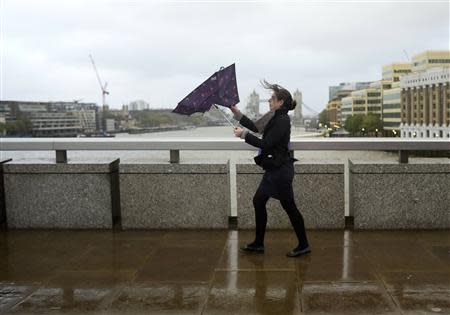 A commuter loses control of her umbrella as she braves the wind and rain while crossing London Bridge in London October 28, 2013. REUTERS/Dylan Martinez