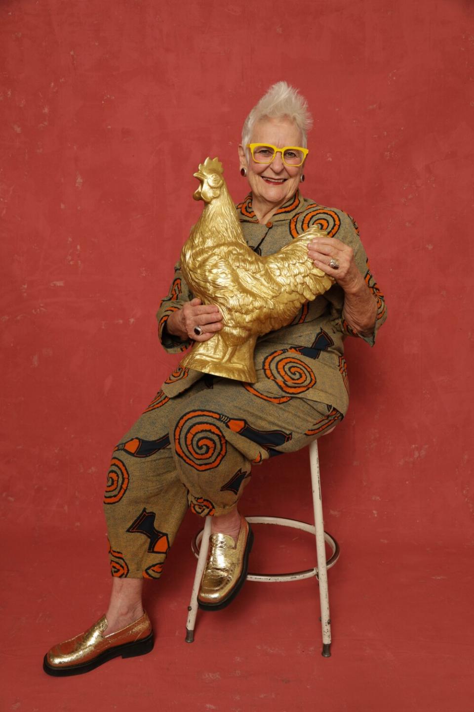 l.a.Eyeworks co-founder Gai Gherardi sitting on a stool in front of a red backdrop holding a gold rooster