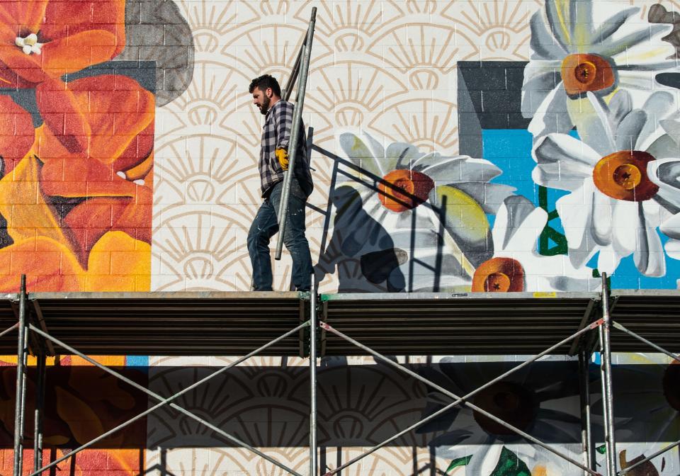 Brad Lewis tears down the scaffolding equipment after the large 300' x 120' mural is completed on the back building of Caliber Collision in Franklin, Tenn., Friday, Nov. 5, 2021.