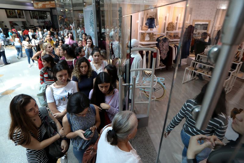 People stand in line outside a store at a mall during the Black Friday sales in Caracas