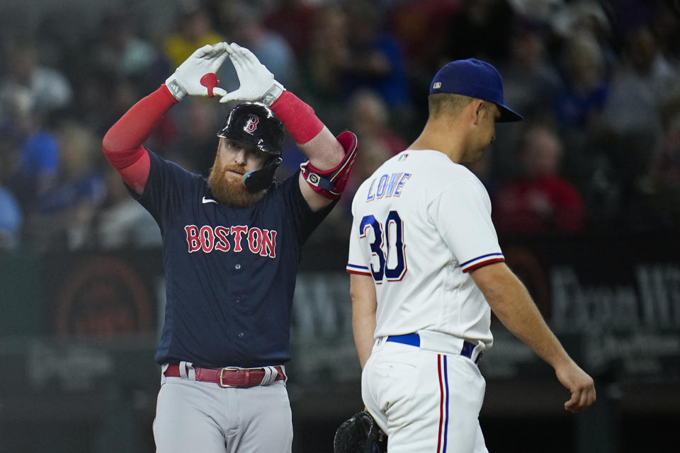 Boston Red Sox's Justin Turner, left, gestures behind Texas Rangers first baseman Nathaniel Lowe after collecting a single during the first inning of a baseball game, Tuesday, Sept. 19, 2023, in Arlington, Texas. (AP Photo/Julio Cortez)