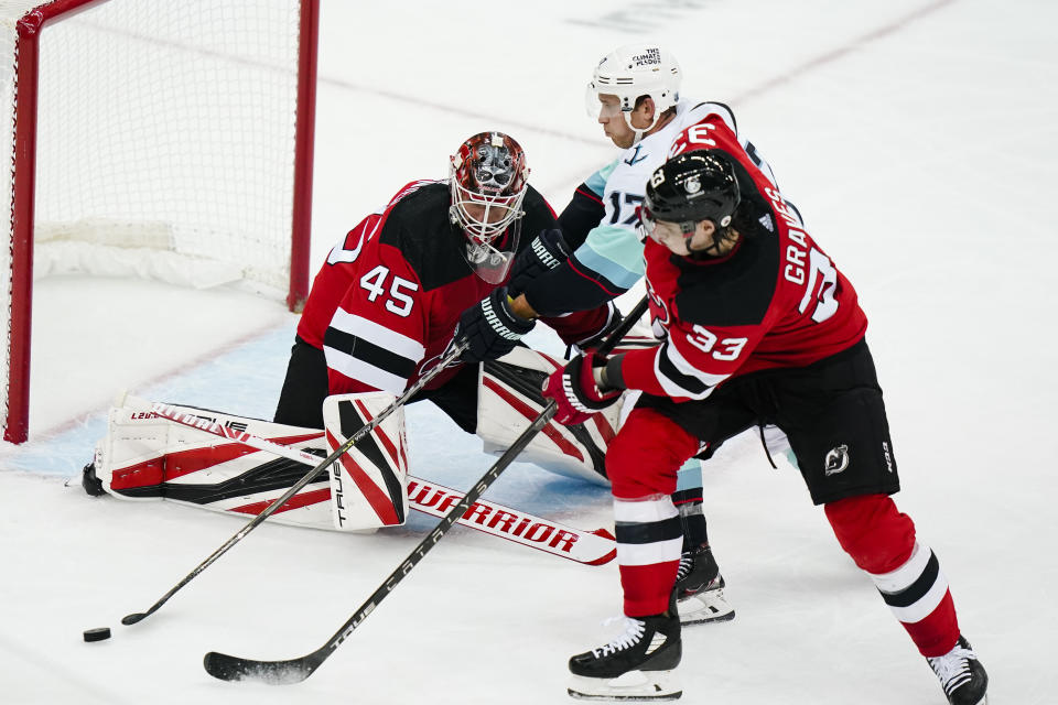 New Jersey Devils goaltender Jonathan Bernier (45) and teammate Ryan Graves (33) defend against Seattle Kraken's Jaden Schwartz (17) during the third period of an NHL hockey game Tuesday, Oct. 19, 2021, in Newark, N.J. The Devils won 4-2. (AP Photo/Frank Franklin II)