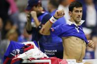 Novak Djokovic of Serbia changes shirts between sets while facing Roger Federer of Switzerland in their men's singles final match at the U.S. Open Championships tennis tournament in New York, September 13, 2015. REUTERS/Eduardo Munoz