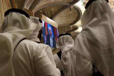 Tea servers watch U.S. President Donald Trump deliver remarks to the Arab Islamic American Summit as they wait to deliver cups of tea in Riyadh, Saudi Arabia May 21, 2017. REUTERS/Jonathan Ernst/Files