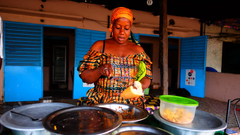 Senegalese street vendor putting ndambe on baguette