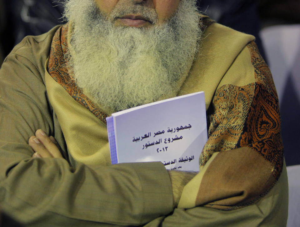 In this Thursday, Jan. 9, 2014 photo, an Egyptian Salafi holds a copy of the new constitution as he attends a conference to hear a lecture entitled “Know Your Constitution," ahead of a two-day vote on a draft amendment in El-Saf village, 50 kilometers (31 miles) south of Cairo, Egypt. Arabic reads, "the constitution of the Arab Republic of Egypt." The conference, held to rally “yes” votes for the charter, highlights a striking alliance that has emerged since the military toppled Islamist President Mohammed Morsi and his democratically elected government last summer. Both the military-backed authorities and the Al-Nour party appear to be benefiting from it, despite the awkwardness. (AP Photo/Amr Nabil)