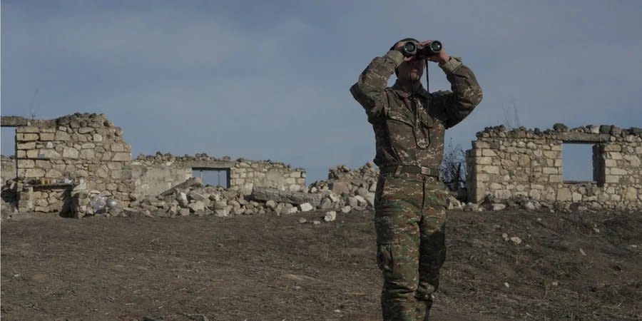 An Armenian soldier looks through binoculars at a combat position near the village of Taghavard in Karabakh, January 2021
