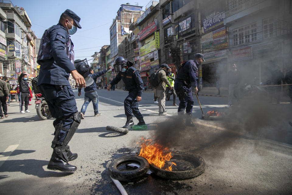 Nepalese policemen clear a road blocked by demonstrators during a general strike in Kathmandu, Nepal, Thursday, Feb. 4, 2021. A general strike called by a splinter faction of the ruling Communist party paralyzed life in Nepal on Thursday, shutting down schools, transportation and markets. Highways were deserted and shops were closed by the strike protesting Prime Minister Khadga Prasad Oli's decision to dissolve Parliament and call new elections. (AP Photo/Niranjan Shrestha)