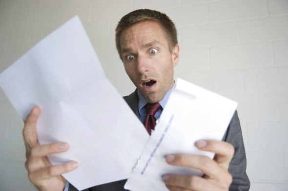 Businessman holds his mouth open in shock as he looks at a document he just got in the mail