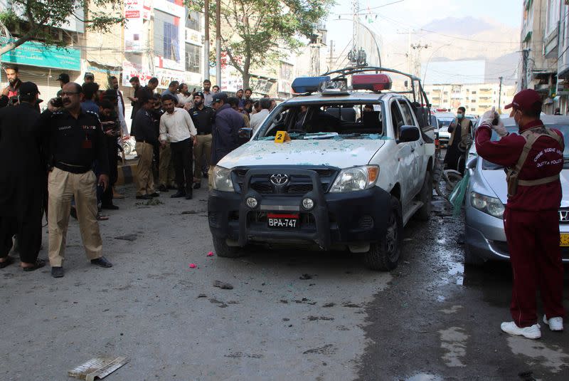 Police officers and members of the crime scene unit gather as they survey after a blast in Quetta