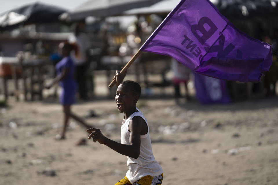 A boy runs as he waves a flag in support of the presidential candidate Kouadio Konan Bertin, during the final campaign rally in Abidjan, Ivory Coast, Thursday, Oct. 29, 2020. Bertin, known as KKB, has presented his candidacy as an independent candidate for the upcoming Oct. 31 election, and said he would not join the boycott proposed by two main opponents of Ivory Coast President Alassane Ouattara. (AP Photo/Leo Correa)