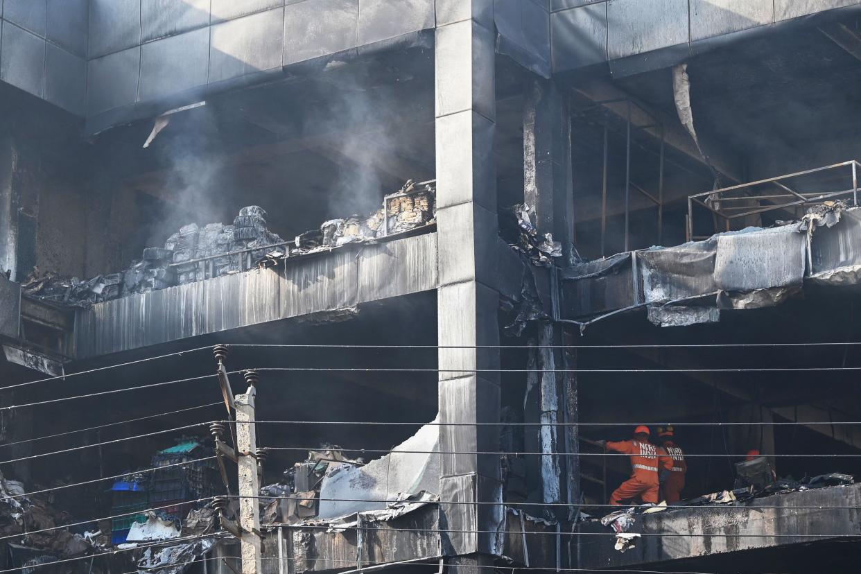 National Disaster Response Force members inspect a commercial building a day after a fire broke out in New Delhi on May 14, 2022. 