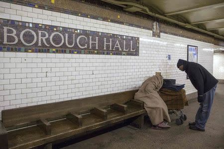 Pastor Gilford Monrose, a volunteer for the Department of Homeless Services survey count, speaks with a man at the Borough Hall subway station in the Brooklyn borough of New York February 10, 2015. REUTERS/Shannon Stapleton