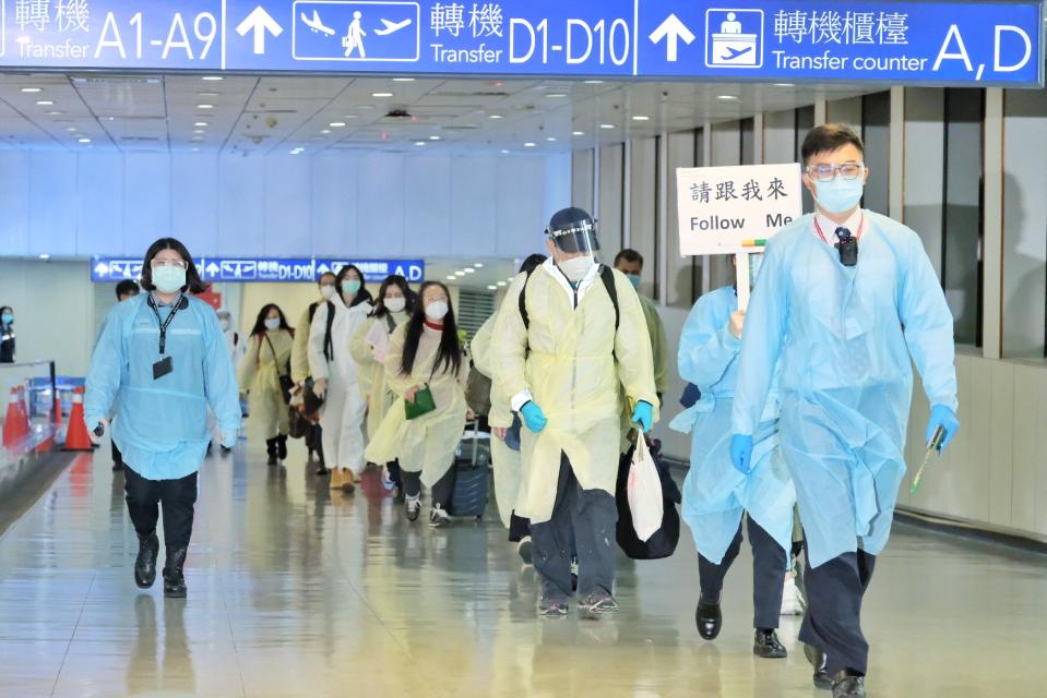 英國返台旅客以每梯次約20人一組方式保持社交距離，由保全著防護裝備全程引導警戒，依序通過移民署證照查驗、提領行李、海關稽查等入境程序。