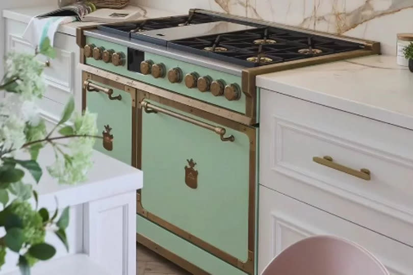 A mint green oven and air vent in between white countertops