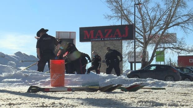 Police officers search the area a day after a body was found outside of Mazaj Lounge & Restaurant in south Calgary.