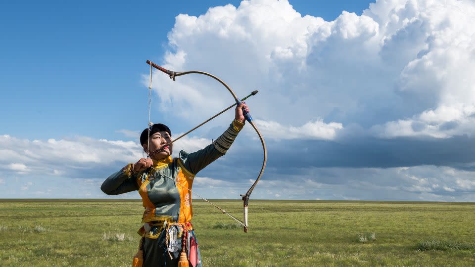A female archer strikes a pose at a small Naadam festival at the Three Camel Lodge in Mongolia's Gobi Desert in 2019. - Alison Wright/Corbis/Getty Images