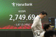 A currency trader talks near the screen showing the Korea Composite Stock Price Index (KOSPI) at a foreign exchange dealing room in Seoul, South Korea, Friday, March 29, 2024. Asian shares were mostly higher Friday in quiet holiday trading, with markets closed in Hong Kong, Sydney, Singapore and India, among other places. (AP Photo/Lee Jin-man)