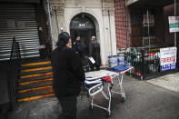 Funeral director Tom Cheeseman, center, and a colleague make a house call to collect a body, Friday, April 3, 2020, in the Brooklyn borough of New York. Cheeseman is picking up as many as 10 bodies per day. Most bodies come from homes and hospitals. (AP Photo/John Minchillo)