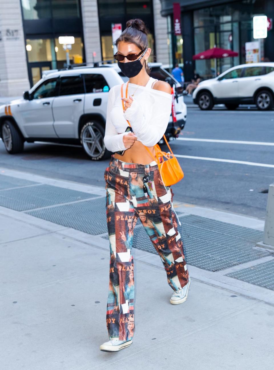 <p>Sin dejar su estilo juvenil y coqueto la modelo lució una mascarilla negra que complementó con un<em> crop</em> top blanco, pantalones a la cadera con estampado de <em>Playboy </em>y un mini bolso color naranja.</p>