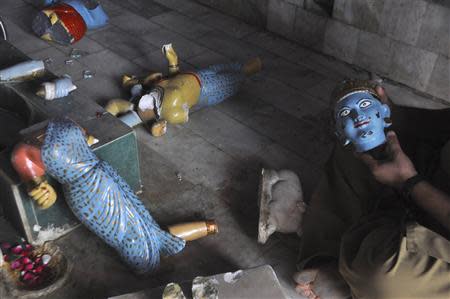 A member of the Hindu community holds a damaged statue inside a temple that was attacked on Saturday night, in Larkana, southern Pakistan's Sindh province, March 16, 2014. REUTERS/Faheem Soormro