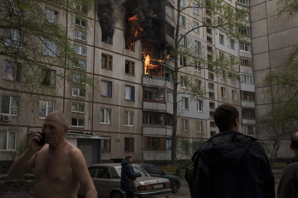 People watch as a residential building burns following a Russian bombardment in Kharkiv, Ukraine, Monday, April 25, 2022. (AP Photo/Felipe Dana)