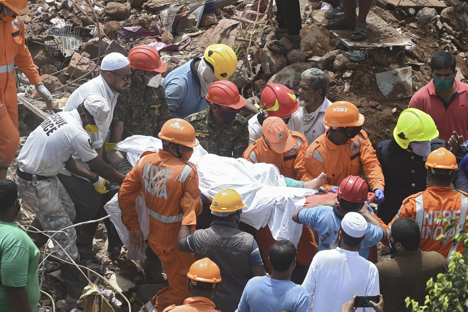 Rescue workers carry the body of a victim who died after a five-storey apartment building collapsed in Mahad. (Photo by PUNIT PARANJPE/AFP via Getty Images)