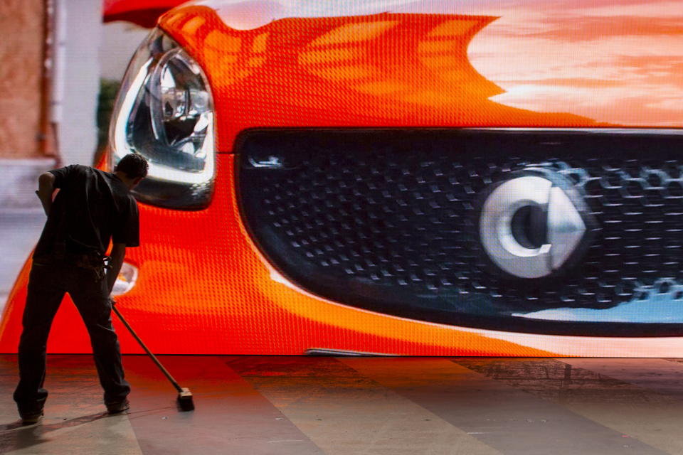 A smart car is seen on a screen while a worker sweeps the stage before the Mercedes-Benz & smart Media Night at the 2015 New York International Auto Show in New York March 31, 2015. REUTERS/Andrew Kelly