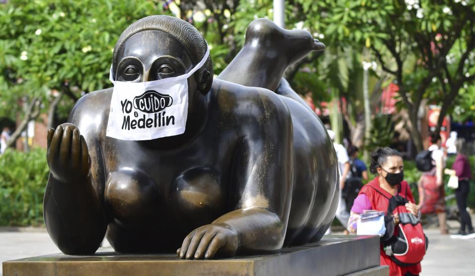 Estatua callejera de Fernando Botero con un tapabocas que dice "Yo cuido a Medellín" en foto del 9 de junio del 2020. Medellín tomó medidas temprano y ha logrado contener el brote de coronavirus. Tiene poco más de 800 contagios y apenas cuatro muertos. (AP Photo/Luis Benavides)