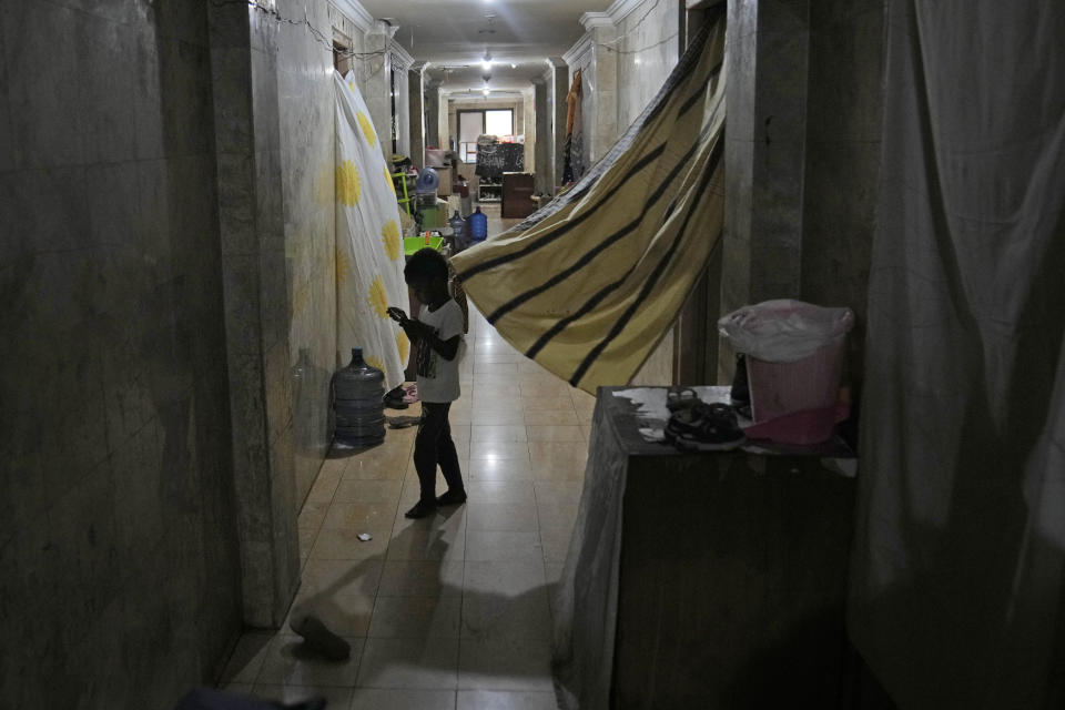 A child plays with a mobile phone in the hallway of Hotel Kolekta, turned into a shelter for refugees, in Batam, an island in northwestern Indonesia, Thursday, May 16, 2024. The former tourist hotel was converted in 2015 into a temporary shelter that today houses 228 refugees from conflict-torn nations including Afghanistan, Somalia, Sudan and elsewhere. (AP Photo/Dita Alangkara)