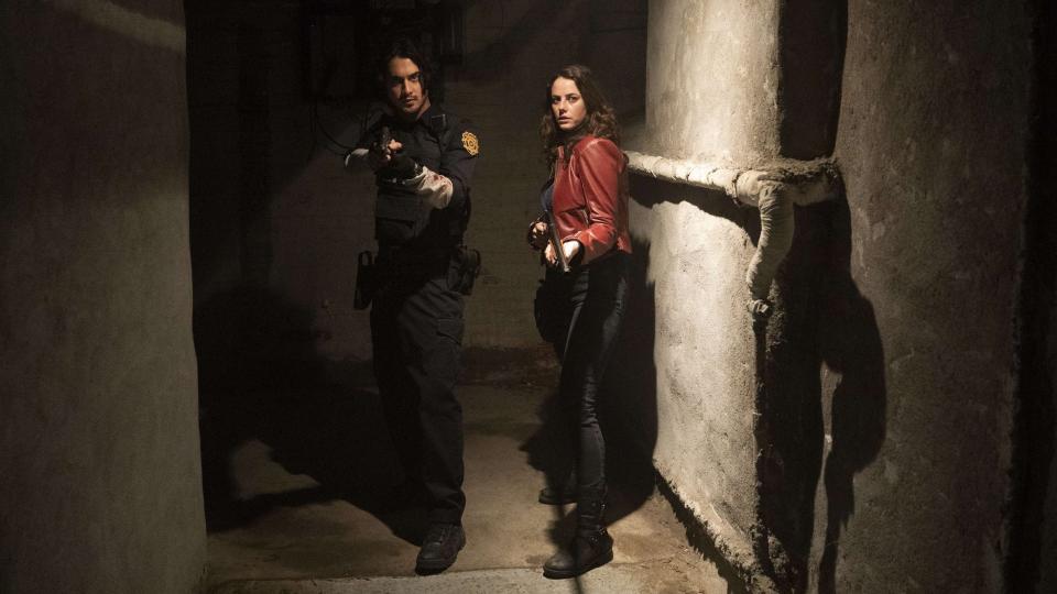 A still from Resident Evil: Welcome to Raccoon City shows Avon Jogia as Leon and Kaya Scodolario as Claire Redfield walking through a tunnel