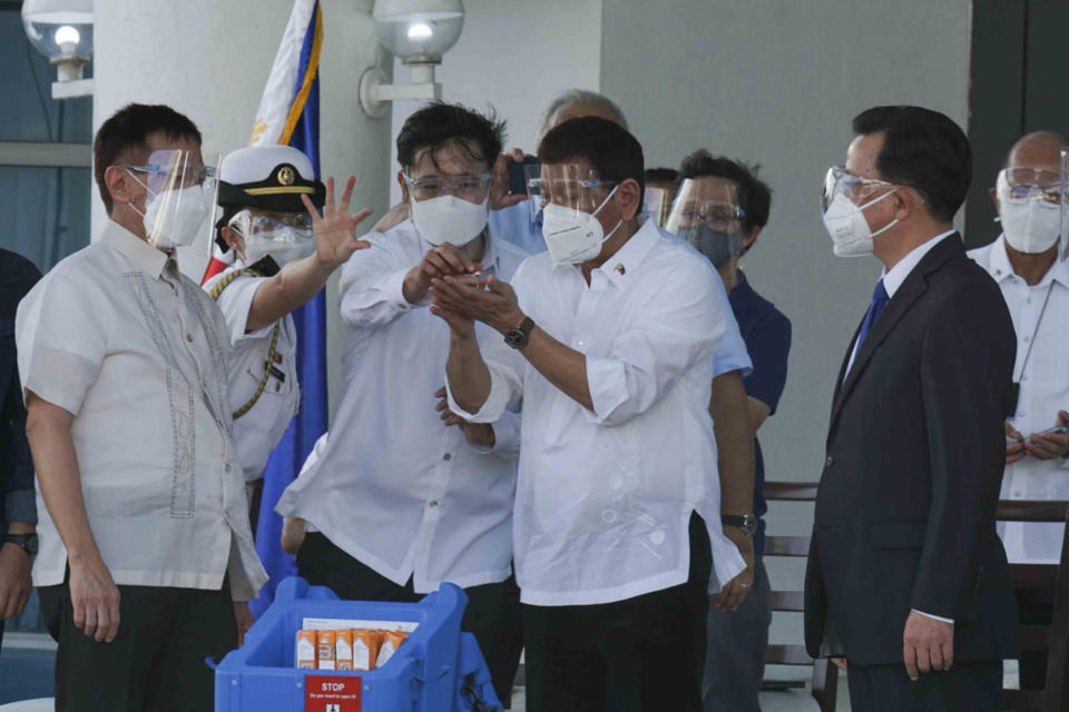 In this photo provided by the Presidential Communications Operations Office-Office of the Global Media Public Affairs, Philippine President Rodrigo Duterte, center, looks at a vial containing the Sinovac vaccine from China as it arrives at the Villamor Air Base in Manila, Philippines on Sunday Feb. 28, 2021. The Philippines is due to receive its first batch of COVID-19 vaccine Sunday, among the last in Southeast Asia to secure the critical doses despite having the second-highest number of coronavirus infections and deaths in the hard-hit region. (PCOO-OGMPA via AP)