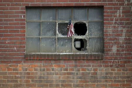 A U.S. flag is stuck in the broken window of a building on the grounds of the now-closed Bethlehem Steel mill in Bethlehem, Pennsylvania, U.S. April 21, 2016. REUTERS/Brian Snyder