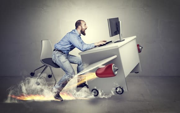 Office worker running along with his rocket-powered desk.