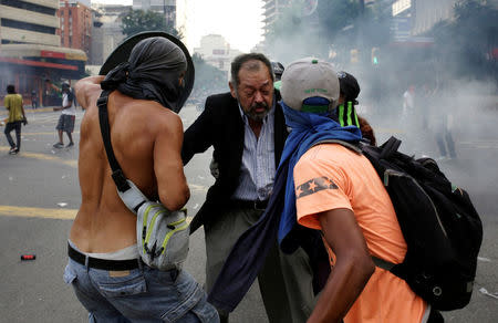 Opposition supporters help an elderly man to cross the street during clashes with security forces in a rally against Venezuela's President Nicolas Maduro in Caracas, Venezuela April 26, 2017. REUTERS/Marco Bello