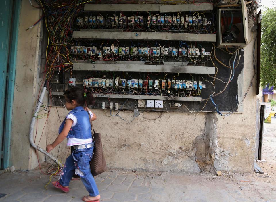 In this photo taken on Sunday, April 27, 2014, a girl walks past an electricity switchboard in Baghdad, Iraq. As parliamentary elections are held Wednesday, more than two years after the withdrawal of U.S. troops, Baghdad is once again a city gripped by fear and scarred by violence. (AP Photo/Karim Kadim)